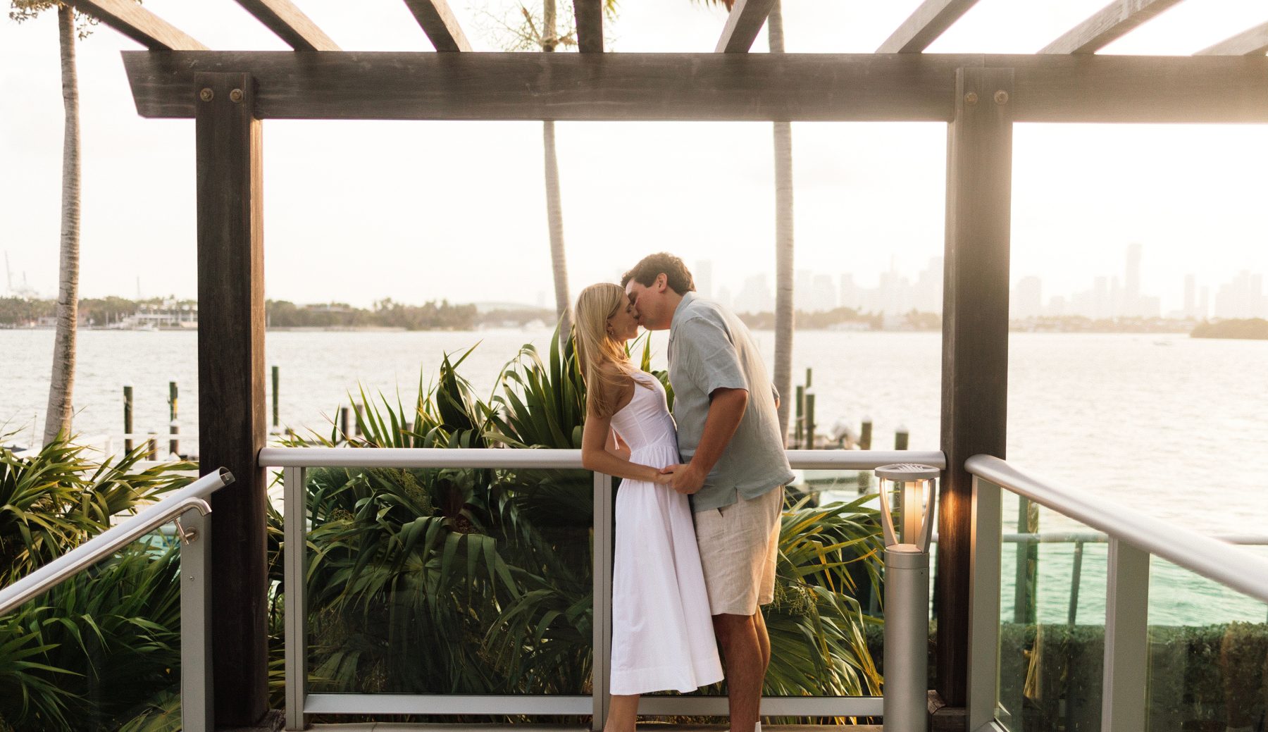 Alexandria and Michael kissing under a pergola by the water in Miami